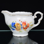 Springer & Co, EPIAG - Checoslováquia(Fundada entre 1918 e 1920 a partir de fábricas nos arredores de Carlsbad). Excepcional molheira em porcelana tcheca da década de 1920. Esmaltagem vítrea na cor branca, corpo bojudo assentado sobre base circular moldada com movimento ondulatório, orlas circundadas por faixa contendo frisos e enrolamentos relevados na própria pasta; faces decoradas com bela composição botânica em estampagem policromada, predominando as tonalidades amarelo, ocre, azul, coral, verde e marsala; contornos ornamentados com aplicação de filetes em douradura; bico vertedor ondulado, alça lateral modelada em voluta. Marca da manufatura no verso. Medidas: Alt.: 8 x Comp.: 14 x Larg.: 9 cm. (A Springer & Co de Elbogen na Boêmia foi formada na década de 1880 e encerrou suas atividades em 1945. Ela foi uma das fábricas fundadoras originais da OEPIAG (mais tarde EPIAG), que era uma associação de olarias formadas pelo governo de Viena em 1918 para promover a venda de cerâmica e porcelana da Boêmia. Foi inicialmente denominado OEPIAG, um acrônimo para Österreichische Porzellan Industrie AG ou Austrian Porcelain Industry, mas foi alterado para EPIAG - Erste Böhemische Porzellan Industrie AG que significa Primeira Indústria de Porcelana da Boêmia - em 1920 após a independência da Checoslováquia).