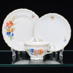 Springer & Co, EPIAG - Checoslováquia(Fundada entre 1918 e 1920 a partir de fábricas nos arredores de Carlsbad). Excepcional trio pra chá em porcelana tcheca da década de 1920. Esmaltagem vítrea na cor branca, bojo campaniforme, levemente evertido, assentado sobre base circular moldada com movimento ondulatório, orla externa circundada por faixa contendo frisos e enrolamentos relevados na própria pasta; face lateral decorada com bela composição botânica em estampagem policromada, predominando as tonalidades amarelo, ocre, azul, coral, verde e marsala; contornos ornamentados com aplicação de filetes em douradura. Padrão decorativo replicado no pires e no prato. Marca da manufatura no verso. Medidas: Xícara: Alt.: 5,5 x Comp.: 12,5 x Larg.: 10 cm. Pires: Diam.: 15,5 cm; Prato.: Diam.: 17,5 cm. (A Springer & Co de Elbogen na Boêmia foi formada na década de 1880 e encerrou suas atividades em 1945. Ela foi uma das fábricas fundadoras originais da OEPIAG (mais tarde EPIAG), que era uma associação de olarias formadas pelo governo de Viena em 1918 para promover a venda de cerâmica e porcelana da Boêmia. Foi inicialmente denominado OEPIAG, um acrônimo para Österreichische Porzellan Industrie AG ou Austrian Porcelain Industry, mas foi alterado para EPIAG - Erste Böhemische Porzellan Industrie AG que significa Primeira Indústria de Porcelana da Boêmia - em 1920 após a independência da Checoslováquia).