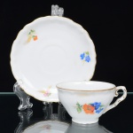 Springer & Co, EPIAG - Checoslováquia(Fundada entre 1918 e 1920 a partir de fábricas nos arredores de Carlsbad). Excepcional xícara para café em porcelana tcheca da década de 1920. Esmaltagem vítrea na cor branca, bojo campaniforme, levemente evertido, assentado sobre base circular moldada com movimento ondulatório, orla externa circundada por faixa contendo frisos e enrolamentos relevados na própria pasta; face lateral decorada com bela composição botânica em estampagem policromada, predominando as tonalidades amarelo, ocre, azul, coral, verde e marsala; contornos ornamentados com aplicação de filetes em douradura. Padrão decorativo replicado no pires. Marca da manufatura no verso. Medidas: Xícara: Alt.: 4,5 x Comp.: 9 x Larg.: 7,5 cm. Pires: Diam.: 15,5 cm; Prato.: Diam.: 12,5 cm. (A Springer & Co de Elbogen na Boêmia foi formada na década de 1880 e encerrou suas atividades em 1945. Ela foi uma das fábricas fundadoras originais da OEPIAG (mais tarde EPIAG), que era uma associação de olarias formadas pelo governo de Viena em 1918 para promover a venda de cerâmica e porcelana da Boêmia. Foi inicialmente denominado OEPIAG, um acrônimo para Österreichische Porzellan Industrie AG ou Austrian Porcelain Industry, mas foi alterado para EPIAG - Erste Böhemische Porzellan Industrie AG que significa Primeira Indústria de Porcelana da Boêmia - em 1920 após a independência da Checoslováquia).