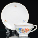 Springer & Co, EPIAG - Checoslováquia(Fundada entre 1918 e 1920 a partir de fábricas nos arredores de Carlsbad). Excepcional xícara para chá em porcelana tcheca da década de 1920. Esmaltagem vítrea na cor branca, bojo campaniforme, levemente evertido, assentado sobre base circular moldada com movimento ondulatório, orla externa circundada por faixa contendo frisos e enrolamentos relevados na própria pasta; face lateral decorada com bela composição botânica em estampagem policromada, predominando as tonalidades amarelo, ocre, azul, coral, verde e marsala; contornos ornamentados com aplicação de filetes em douradura. Padrão decorativo replicado no pires. Marca da manufatura no verso. Medidas: Xícara: Alt.: 5,5 x Comp.: 12,5 x Larg.: 10 cm. Pires: Diam.: 15,5 cm. (A Springer & Co de Elbogen na Boêmia foi formada na década de 1880 e encerrou suas atividades em 1945. Ela foi uma das fábricas fundadoras originais da OEPIAG (mais tarde EPIAG), que era uma associação de olarias formadas pelo governo de Viena em 1918 para promover a venda de cerâmica e porcelana da Boêmia. Foi inicialmente denominado OEPIAG, um acrônimo para Österreichische Porzellan Industrie AG ou Austrian Porcelain Industry, mas foi alterado para EPIAG - Erste Böhemische Porzellan Industrie AG que significa Primeira Indústria de Porcelana da Boêmia - em 1920 após a independência da Checoslováquia).