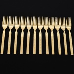 Belíssimo conjunto de garfos grandes confeccionadas em metal, dotadas de profusa ornamentação em douradura; lâmina com dorso serrilhado, cabo relevado com decoração geométrica repetitiva em recortes simétricos losangulares e formas estilizadas, inseridos em campo texturizado. Fabricação coreana, marca da manufatura no verso. Composto de doze(12) unidades. Med.: Comp. 18,5 cm.