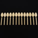 Belíssimo conjunto de colheres para sobremesa confeccionadas em metal, dotadas de profusa ornamentação em douradura; lâmina com dorso serrilhado, cabo relevado com decoração geométrica repetitiva em recortes simétricos losangulares e formas estilizadas, inseridos em campo texturizado. Fabricação coreana, marca da manufatura no verso. Composto de doze(12) unidades. Med.: Comp. 15,5 cm.