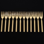 Belíssimo conjunto de garfos para sobremesa confeccionadas em metal, dotadas de profusa ornamentação em douradura; lâmina com dorso serrilhado, cabo relevado com decoração geométrica repetitiva em recortes simétricos losangulares e formas estilizadas, inseridos em campo texturizado. Fabricação coreana, marca da manufatura no verso. Composto de doze(12) unidades. Med.: Comp. 16 cm.