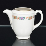 CHODZIEZ PORCELAIN, Chodziez - Polônia(Fundada em 1852 ou 1854, por Hermann Müller e Ludwik Schnorr). Leiteira em porcelana polonesa da década de 1940; esmaltagem vítrea na cor branca, decorada com faixas contendo padrão floral, aplicado em estampagem policromada, borda delimitada por barrado contínuo relevado na própria pasta, corpo oval alongado assentado sobre base circular recortada, tampa ligeiramente abaulada encimada por puxador em forma de flor, bico vertedor curto revirado para fora, alça lateral em voluta com descanso de polegar relevado em folhagem, contornos realçados com filete em douradura. Marca da manufatura no verso. Medidas: Alt.: 9 x Comp.: 12,5 x Larg.: 7 cm.