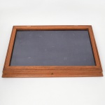 Caixa expositora em madeira, de formato retangular, com tampa articulada em vidro e interior revestido em tecido, destinada à apresentação de objetos, com base moldurada e fecho frontal.