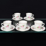 Porcelana Real, Mauá - SP(Fundada em 1943 por Fritz Erwin Schmidt). Conjunto de xícaras para café em porcelana nacional, esmaltação branca, decorada com flores em estampagem policromada, predominando as tonalidades rosa e verde, bojo oval com alça lateral em voluta, borda contornada por friso em douradura, padrão decorativo replicado no pires. Marca da manufatura no verso. Composto de cinco(05) unidades. Medidas: