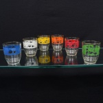 Conjunto composto por seis(06) copos em vidro transparente, de formato cilíndrico levemente afunilado, decorados com faixa colorida em policromia aplicada por serigrafia, apresentando motivo de frutos estilizados. Medidas: