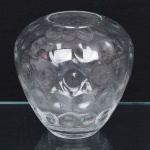 Vaso em vidro incolor, de corpo globular com boca circular ampla e borda levemente espessada. Superfície interna com decoração em relevo moldado, composta por depressões circulares repetidas (padrão tipo bolhas/lentes), distribuídas de forma regular por toda a parede.  Peça obtida por prensagem em molde. Medidas: