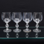 Conjunto de taças, para vinho, em cristal, diáfano e incolor, bojo liso, fuste em anel intermediário multifacetado, apoiado sobre base circular moldada com sulcos verticais. Composto de quatro unidades. Medidas: