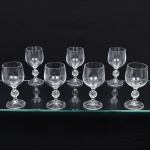 Conjunto de taças, para licor, em cristal, diáfano e incolor, bojo liso, fuste em anel intermediário multifacetado, apoiado sobre base circular moldada com sulcos verticais. Composto de sete(07) unidades. Medidas: