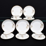 Porcelana Renner, Porto Alegre - RS(Fundada em 1937). Conjunto de xícaras para chá em porcelana nacional, série Médaillon; esmaltação branca, decoração floral em estampagem, predominando as tonalidades castanho, branco e preto, bojo cilíndrico com alça lateral oval, borda contornada por faixa em douradura, padrão decorativo replicado no pires. Marca da manufatura ao fundo. Composto de cinco(05) unidades. Medidas: