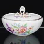 Fábrica de Porcelana São João, Recife - Pernambuco. (Fundada em 1947, ativa até 1968). Pote com tampa em porcelana nacional, esmaltação branca, decorada com composição botânica em policromia, bojo hemisférico, tampa reta encimada por pega estilizada, contornos realçados com douradura(apresentam degaste). Marca da manufatura ao fundo. Medidas: