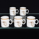Porcelana Renner, Porto Alegre - RS(Fundada em 1937). Conjunto de xícaras para café em porcelana nacional, série Médaillon; esmaltação branca, decoração floral em estampagem, predominando as tonalidades castanho, branco e preto, bojo cilíndrico com alça lateral oval, borda contornada por faixa em douradura. Conjunto apresenta perda dos pires. Marca da manufatura ao fundo. Medidas: