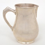 FRACALANZA. Jarra confeccionado em metal espessurado à prata, bojo de perfil balaústre sobre base circular, bico vertedor ligeiramente revirado para fora, alça lateral curvada, borda superior relevada com fileira frisos intercalados por fitas cruzadas. Marca da manufatura ao fundo. Necessita polimento. Medidas: