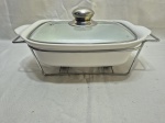 Travessa retangular em porcelana refratária com tampa em vidro e rechaud em aço. Medindo a travessa 32cm x 19cm x 7cm de altura.