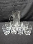 Jarra de água, suco com 8 copos em vidro incolor moldado. Medindo a jarra 12cm x 22cm de altura e os copos 7,5cm x 9,5cm de altura.
