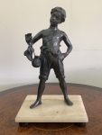 Escultura em petit bronze representando menino com calçados na mão apoiado sobre base em pedra clara ônix. Apresenta discreto restauro na dobra do braço, que não compromete e nem deprecia a peça. Altura: 42cm. Medidas da base: 20x26cm.