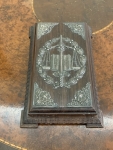 Porta-bloco de notas em madeira de jacarandá com aplicações em prata de lei representando símbolos da Justiça com destaque para a inscrição LEX, balança e espada. Medidas 20x12cm.