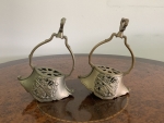 Par de estribos antigos em bronze, com armação vazada e alças trabalhadas, apresentando na face frontal aplicação em relevo com instrumentos musicais entrelaçados por ramos decorativos. Parte superior com inscrição interna `DEPOSE`. Altura 18cm.