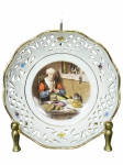 PORCELANA BAVARIA, um (1) bowl confeccionado em porcelana alemã na tonalidade branca, decoração central com cena figurativa (personagem à mesa em ambiente doméstico) em policromia, pequenas flores e folhagens e galeria em vazados, borda filetada em ouro com falhas na douração, medindo 4x12,5cm.