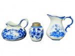 PORCELANA DELFT, três (3) peças confeccionadas em porcelana na tonalidade branca com decoração típica holandesa de elementos florias e paisagens na tonalidade azul, sendo 2 cremeiras e 1 saleiro, maior medindo 7,5cm e menor 5cm.