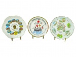 PORCELANAS, três (3) pratos decorativos souvenir confeccionados em porcelanas, sendo: A) um (1) prato com borda recortada, com vistas e inscrição Souvenir de Belgique / Gedenkens van België, medindo 21cm; B) um (1) prato Lembrança do 3º Aniversário, com desenho de caravela e inscrições na borda, medindo 20cm e C) um (1) prato com borda recortada, com mapa ilustrado e inscrição Record dAndorra  La Vella, bicado na borda, medindo 21cm.