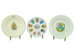 PORCELANAS e FAIANÇA, três (3) pratinhos decorativos, sendo: A) um (1) pratinho em faiança Ottawa  Canada, com brasão e borda recortada, medindo 18,5cm; B) um (1) pratinho com escudos/heráldica ao redor e vista ao centro, medindo 17cm e C) um (1) pratinho com borda em relevo e brasão policromado ao centro, medindo 19,5cm.