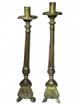 ARTE SACRA, par (2) de castiçais de altar confeccionados em metal dourado, corpo cinzelado em caneluras, base tripoide, cinzelado por elementos florais e figuras sacras relevadas, apresentam mossas, vendido no estado, medindo 44cm de altura.