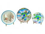 PORCELANAS, conjunto com três (3) pratos decorativos temáticos confeccionados em porcelana branca (Brasil/Rio de Janeiro), sendo: A) um (1) prato comemorativo com imagem do Papa e inscrição III Encontro Mundial do Papa com as Famílias  Brasil  4 a 7 Outubro de 1997  Rio de Janeiro, medindo 19cm; B) um (1) prato BRASIL  Rio de Janeiro, com montagem de pontos turísticos e mapa do Brasil ao centro, medindo 20cm e C) um (1) prato menor BRASIL  Rio de Janeiro, com paisagens e mapa do Brasil ao centro, medindo 15cm.
