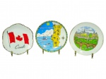 PORCELANAS, conjunto com três (3) pratos decorativos souvenir confeccionadas em porcelana branca, sendo: A) um (1) prato com borda recortada, decoração com bandeira do Canadá e inscrição Canada, medindo 18,5cm; B) um (1) prato Portugal, com mapa ilustrado e cena marítima, borda decorada, medindo 19,5cm e C) um (1) prato Luxembourg, com paisagem ilustrada e filete na borda, medindo 19cm.