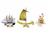 ESCULTURAS, lote com três (3) esculturas representando barcos de modelos, tamanhos, decorações e materiais distintos, sendo: A) 1 confeccionado em bronze, medindo 23x18,5cm, B) 1 confeccionado em concha marítima e madeira, medindo 17x12cm e C) 1 em madeira pintada, apresentando quebra na vela, medindo 15x16cm.