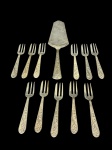 METAL PRATEADO, doze (12) peças para bolo confeccionadas em metal espessurado a prata com cabo cinzelado por elementos florais relevados, sendo 1 pá para bolo e 11 garfos para bolo, algumas peças com falhas na prateação.