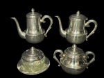 METAL PRATEADO, serviço para chá/café confeccionado em metal espessurado a prata da manufatura WOLFF, corpo liso, tampa escalonada com pega no feitio de pinha, alças curvas finalizadas em volutas, sendo: A) 1 bule para chá, medindo 17x22x9cm, B) 1 bule para café, medindo 18x22x7,5cm, C) 1 açucareiro, medindo 11,5x16x7,5cm e D) 1 manteigueira com recipiente em cristal com fundo estrelado, medindo 10x8cm.