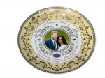 PORCELANA INGLESA, um (1) prato comemorativo confeccionado em porcelana na tonalidade branca, produzido para celebrar o casamento de HRH Henry Charles Albert David Mountbatten-Windsor e Rachel Meghan Markle, datado de 2018, com decoração policromada, retrato central do casal e rica ornamentação em dourado, azul e sépia. Verso marcado Elgate Products Ltd., Designed in England", medindo 20,5cm.
