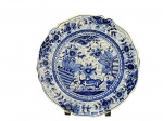 LUIZ SALVADOR (Itaipava), um (1) prato decorativo confeccionado em faiança vitrificada na tonalidade branca com pintura floral na tonalidade azul, borda em ondulações com pequeno bicado na borda, medindo 25,5cm.
