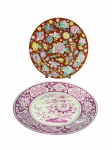 PORCELANAS, lote com dois (2) pratos decorativos, sendo: A) 1 confeccionado em porcelana oriental na tonalidade branca, esmaltagem vermelha com rica decoração floral em policromia, medindo 26,5cm, selo oriental no verso e B) 1 confeccionada em porcelana na tonalidade branca com pintura floral e vegetalista na tonalidade roxa, medindo 25,5cm, assinado no verso.