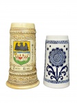 PORCELANAS, lote com dois (2) tankards confeccionados em porcelana da manufatura CERAMARTE, sendo: A) 1 com relevo ornamental e brasão decorativo, inscrita Entre Rios, em tonalidade bege, moldado por elementos vegetalistas e perolados, medindo 20,5x13,5x7,5cm e B) 1 decorado por elementos florais e vegetalistas na tonalidade azul cobalto, medindo 16,5x12x7cm.