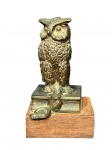 ESCULTURA, uma (1) escultura confeccionada em bronze representando coruja apoiada sobre livro com base em madeira, medindo 14cm de altura.