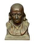 ESCULTURA, uma (1) escultura com cofre confeccionada em metal com patina na tonalidade bronze representando Benjamin Franklin, que frequentemente é utilizado como um cofre de moedas vintage, acompanha chave, medindo 14cm.
