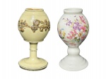 PORCELANA e FAIANÇA, duas (2) cuias para chimarrão, sendo: A) 1 confeccionada em porcelana na tonalidade branca, corpo bojudo, haste gomada e base circular escalonada, decorado por flores e folhagens em policromia e borda com fio de cabelo, medindo 14cm de altura e B) 1 em faiança esmaltada na tonalidade cinza, decorada por guirlanda floral em monocromia com realces em prata, medindo 14cm.