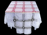 CAMA, MESA & BANHO, uma (1) toalha de mesa quadrada confeccionada em tecido na tonalidade branca, decorada por módulos quadrados intercalados por trabalhos em rendas vazadas e borda em recortes, medindo 224x224