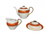 PORCELANA MONTE ALEGRE, três (3) peças, sendo: A) 1 bule para chá, medindo 14x22,5x9cm, B) 1 manteigueira, medindo 7x17x10cm e C) 1 leiteira, medindo 11x15x7cm, confeccionadas em porcelana nacional com espessa faixa na tonalidade abóbora, decorada por guirlanda vegetalista e volutas com arremates em vasta douração.