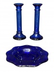 VIDROS, lote com três (3) peças confeccionadas em vidro na tonalidade azul, sendo: A) 1 par de castiçais, corpo cilíndrico, apoiada sobre base circular cônica, medindo 20cm de altura e B) 1 cinzeiro com bordas em ondulações, medindo 20,5cm de diâmetro.