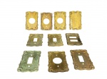 BRONZES, nove (9) espelhos de acabamento para interruptores e tomadas, confeccionadas em bronze, cinzelado por elementos vegetalistas em relevo com recortes na borda, medindo 11,5x7,5cm. Necessitam limpeza, vendidos no estado da foto.