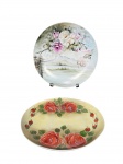 PORCELANAS, dois (2) pratos decorativos confeccionados em porcelana branca com pintura floral de modelos distintos em policromia, medindo 24cm de diâmetro.
