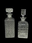 CRISTAL e VIDRO, lote com duas (2) garrafas para whisky, sendo: A) 1 confeccionada em cristal translucido com lapidação de elementos geométricos em baixo relevo e fundo estrelado, apresenta sinais de fungos, medindo 25cm de altura e B) 1 confeccionado em vidro translucido com moldagem em bico de jaca, medindo 25cm de altura.