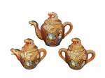 PORCELANA SATZUMA, parte de serviço para chá, sendo: A) 1 bule para chá, medindo 15,5x19x8cm, B) 1 leiteira com tampa, medindo 11,5x13,5x6cm e C) 1 açucareiro, medindo 12x13,5x6cm, confeccionadas em porcelana oriental na tonalidade branca com esmaltagem na tonalidade marrom, decorada por figuras Arhats/Deidades, personagens da mitologia e folclore asiático que simbolizam boa sorte e felicidade, esmaltados em policromia com realces em ouro.