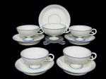 Jean Pouyat (A família Pouyat esteve envolvida na porcelana desde o século XVIII em Limoges, França), cinco (5) xícaras para chá com seus respectivos pires confeccionadas em fina porcelana francesa na tonalidade branca decorada por filetes na tonalidade azul, medindo 5x11x9,5cm.1 píres com ímperceptível bicado.