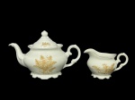 PORCELANA SCHMIDT, duas (2) peças, sendo: A) 1 bule para chá, medindo 15x24x12cm e B) 1 leiteira, medindo 9x14x8,5cm, confeccionadas em porcelana nacional na tonalidade branca com pintura de folhagens em monocromia na tonalidade marrom e borda filetada em ouro.