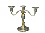 METAL PRATEADO, um (1) candelabro para três velas confeccionado em metal espessurado a prata com banho novo, hastes curvas, corpo torneado com partes em metal dourado, apoiado sobre base escalonada em recortes com fundo em veludo, medindo 19x23cm.